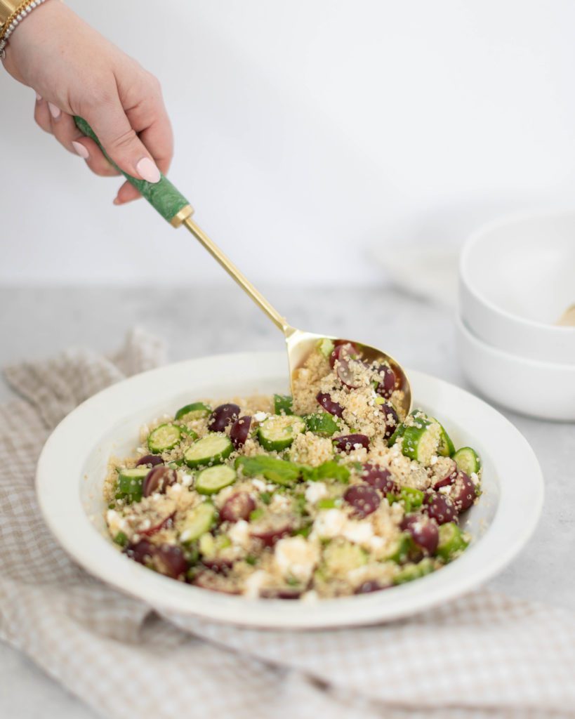 hand scooping out minted feta quinoa salad