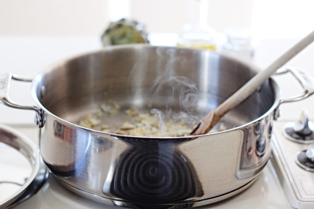 Onions and garlic sauteeing in large metal saucepan 