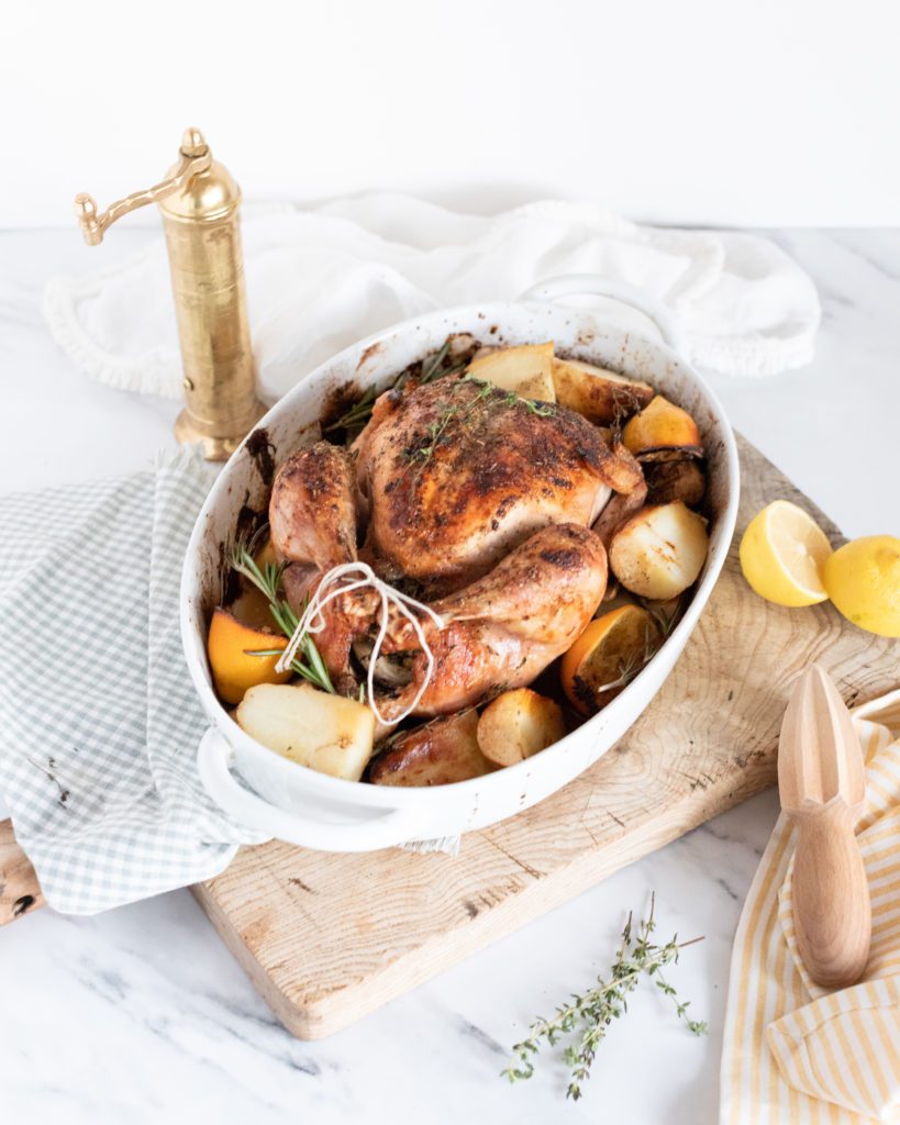 Greek Roasted Chicken & Potatoes in a baking dish with fresh lemons 