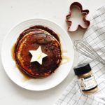Gingerbread pancakes with star shaped butter on top, a gingerman cookie cutter on the table beside, and a jar of epicure gingerbread spice