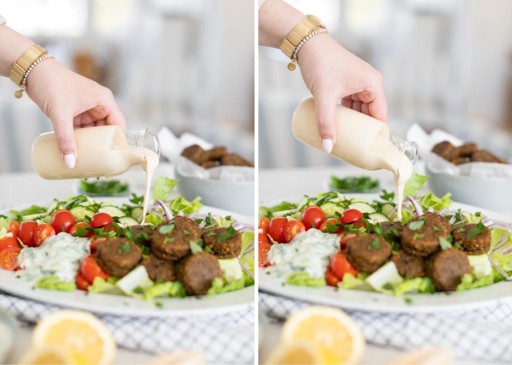 hand pouring Lemon Garlic Tahini Dressing over a falafal salad 