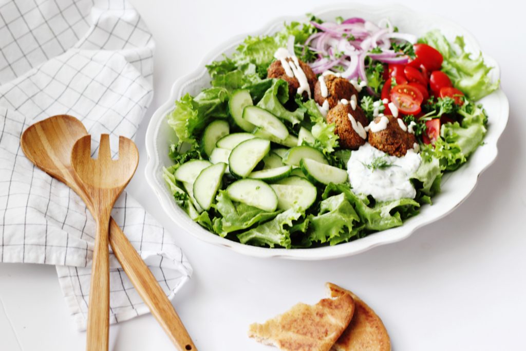 Falafel Salad in white bowl with wooden spoons