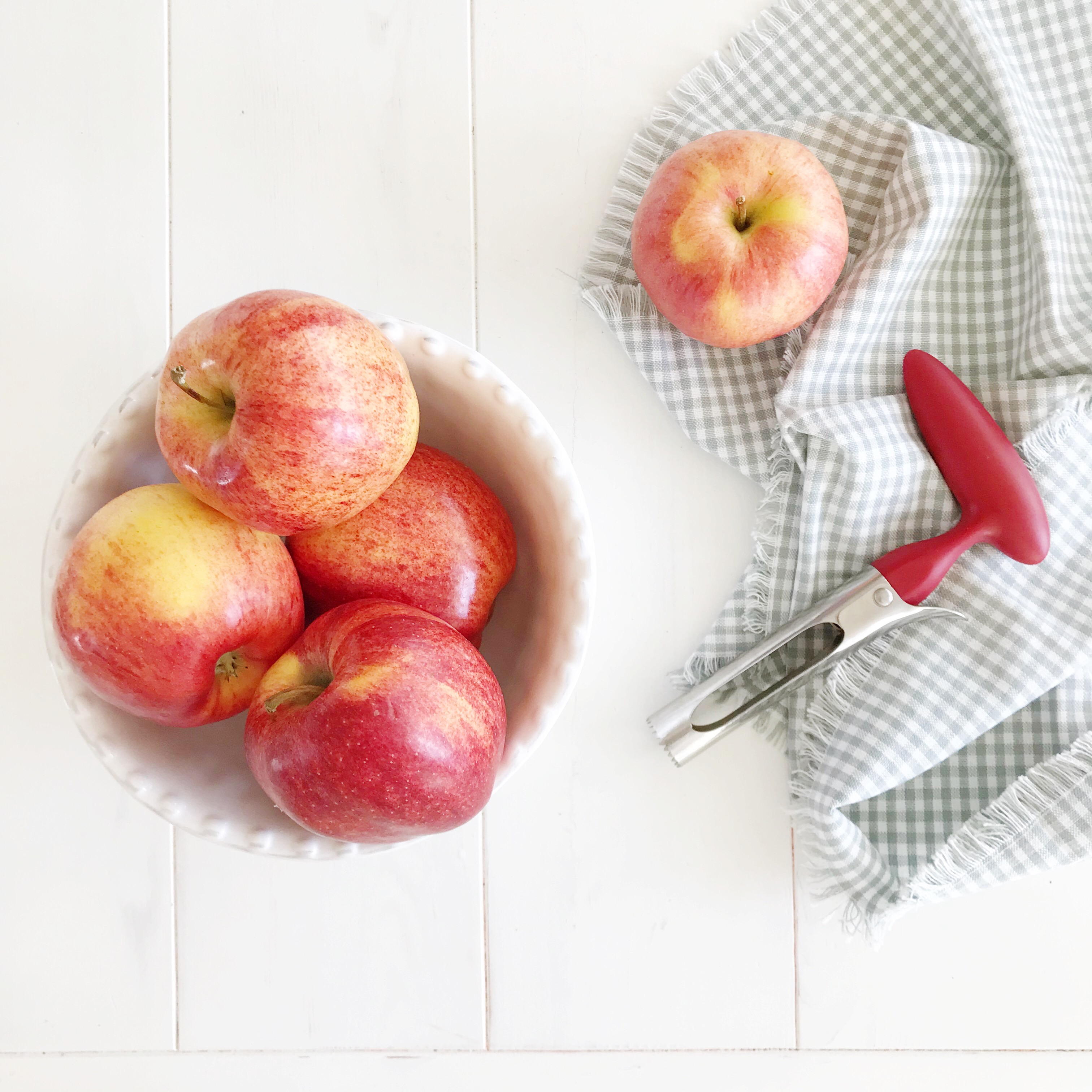 bowl of red apples with an apple corer tool