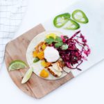 fish tacos on a marble and wooden serving board with apple cilantro slaw