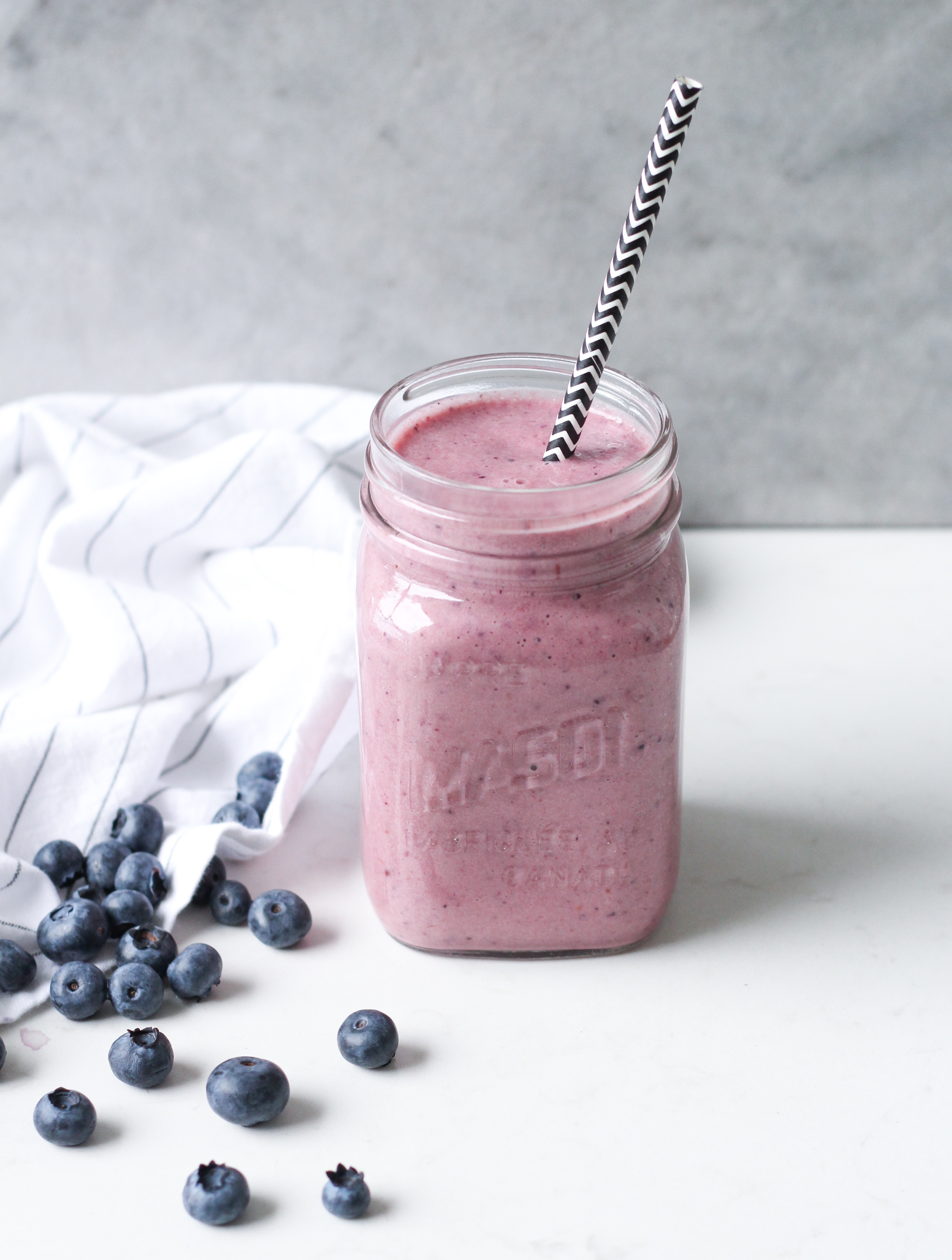 Blueberry cream smoothie in mason jar with straw
