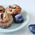 plate of three plum oat bran muffins with two whole plums