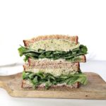 plant based sandwich with green lettuce on a wooden serving block