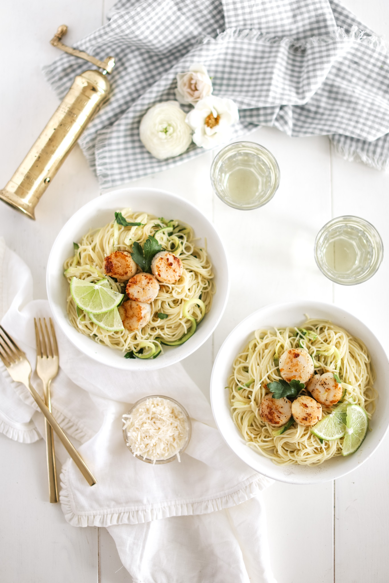 lime capellini pasta in two bowls with glasses of wine