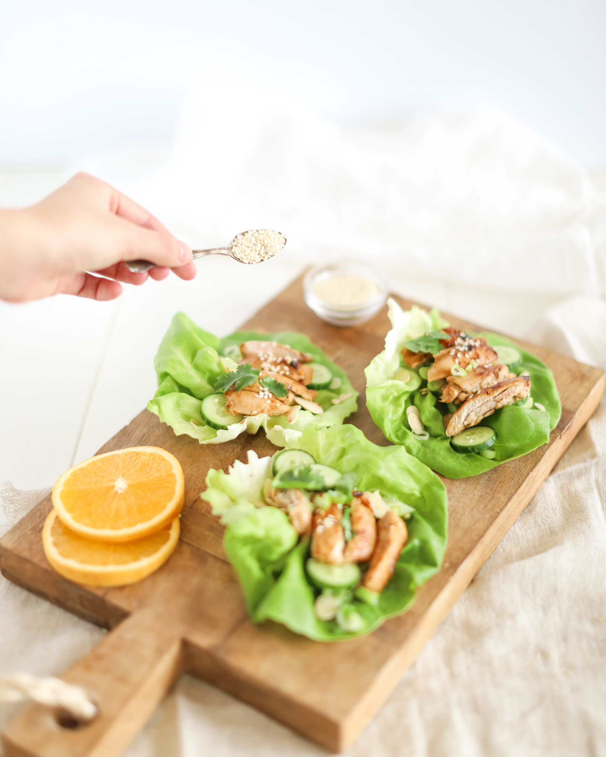 orange chicken lettuce wraps a hand topping with sesame seeds