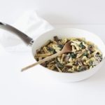 vegan kale mushroom pasta in a white pan on a white surface