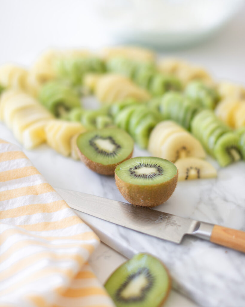 fresh yellow and green kiwi slices on a cutting board with knife