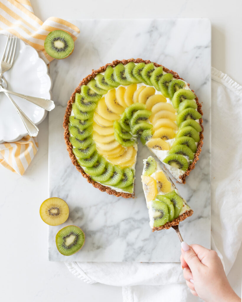 Kiwi Yogurt Tart by Tori Wesszer from Fraiche Living in a tart pan with layers of yellow and green kiwi fruit on top 