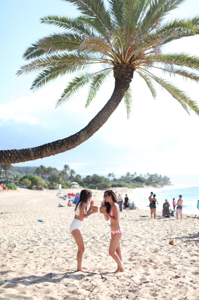 Tori Wesszer and Jillian Harris sip coconut water out of coconuts on the beaches of O'ahu!