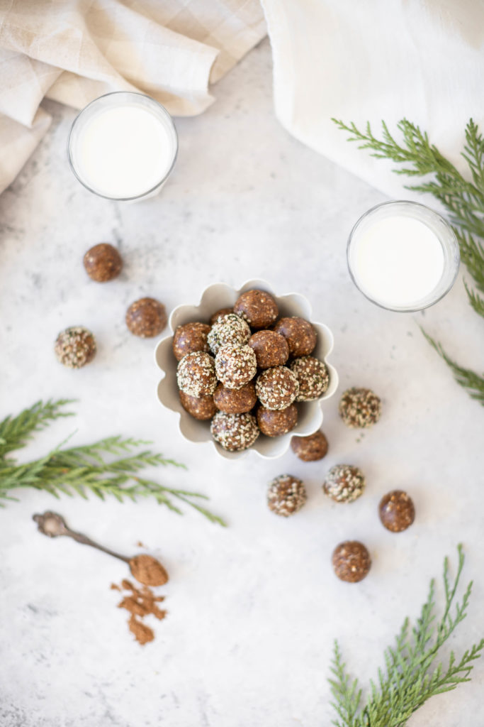 gingerbread energy bites in bowl with glasses of milk