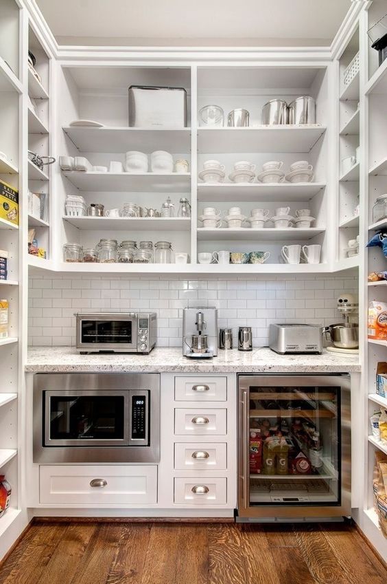 white kitchen butler pantry with microwave, wine fridge, small appliances and open shelving space for all of the kitchen dishes