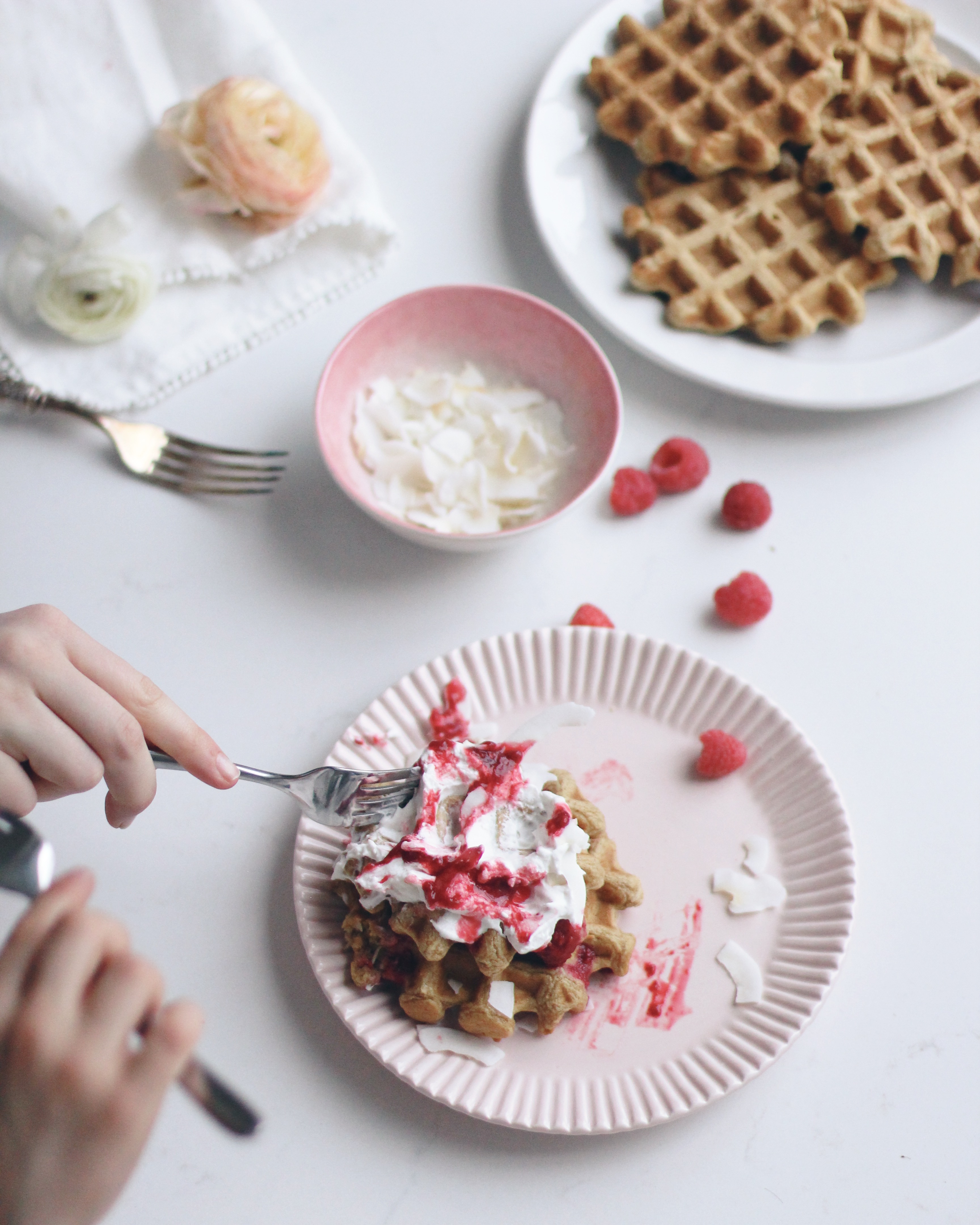 Messy pink plate of coconut waffles .