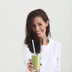 green smoothie in a glass held by Tori from Fraiche Living