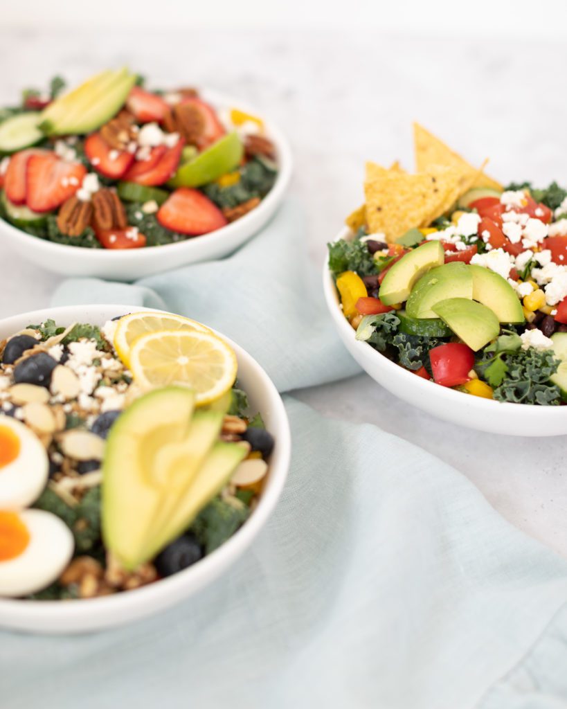 three different salad bowls with fresh vegetables and fruit