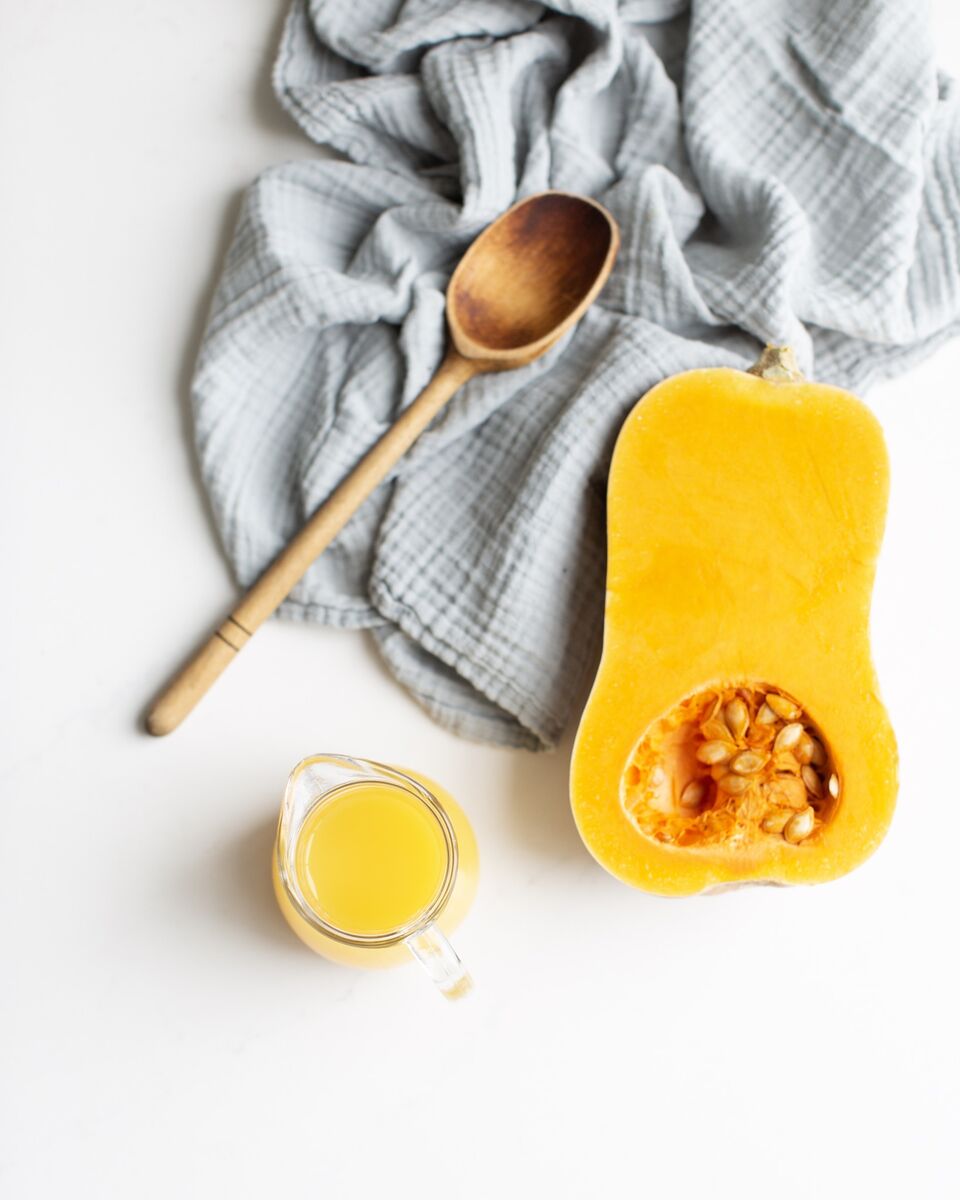 Butternut squash, orange juice and an antique wooden spoon for making Orange Butternut Squash Soup