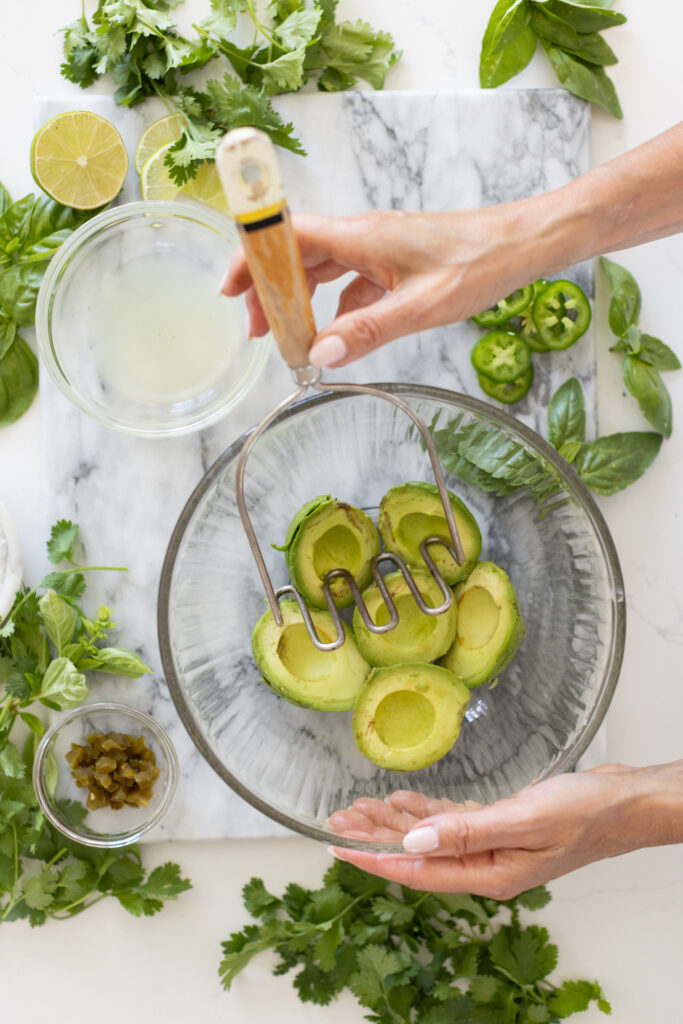 bowl of avocados being smashed into guacamole.