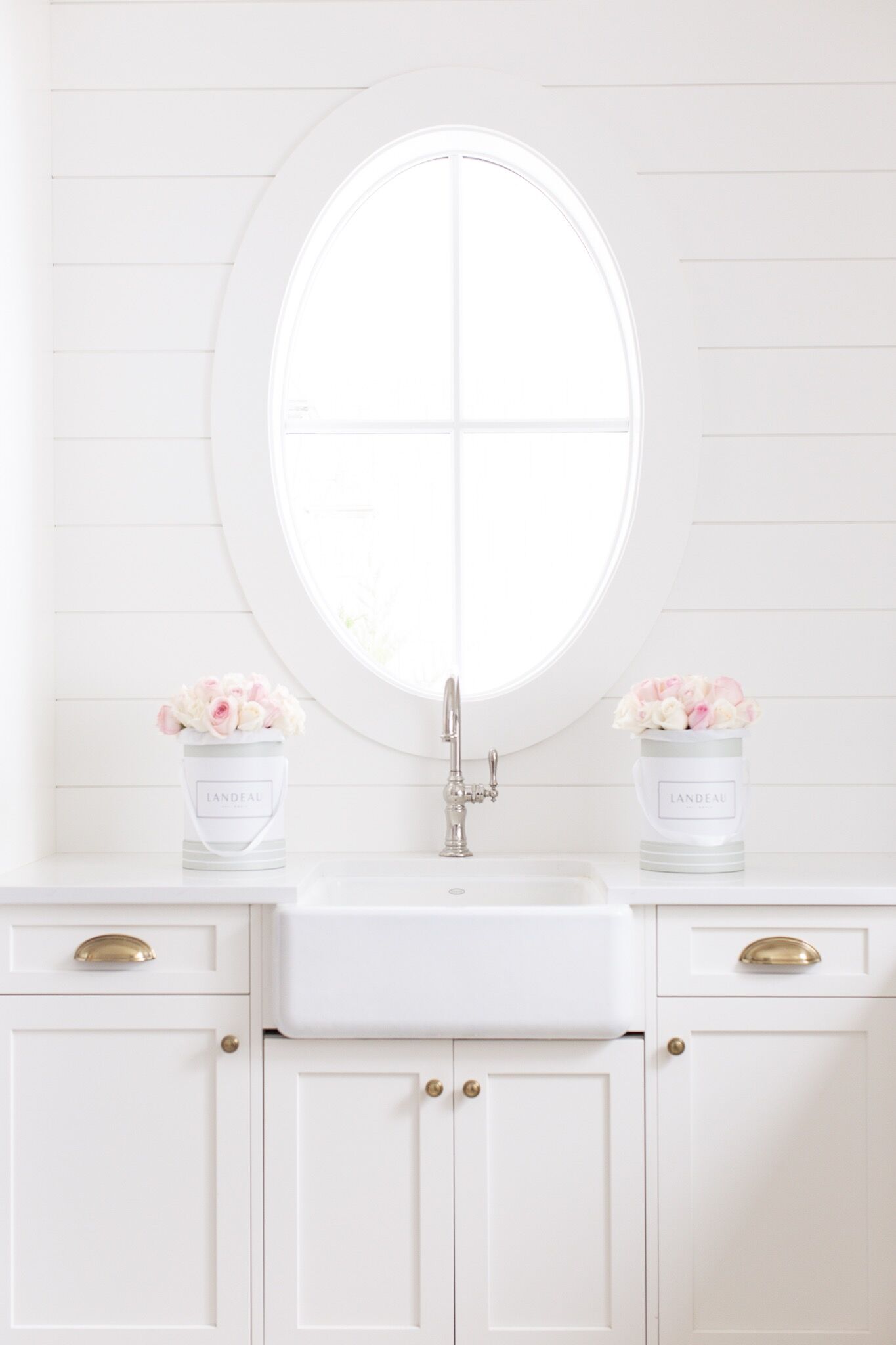 White shiplap laundry room with polished nickel faucet, farmhouse sink, oval window and brass hardware with buckets of pink roses! Give Landeau flower Valentine's giveaway on the Fraiche Nutrition blog