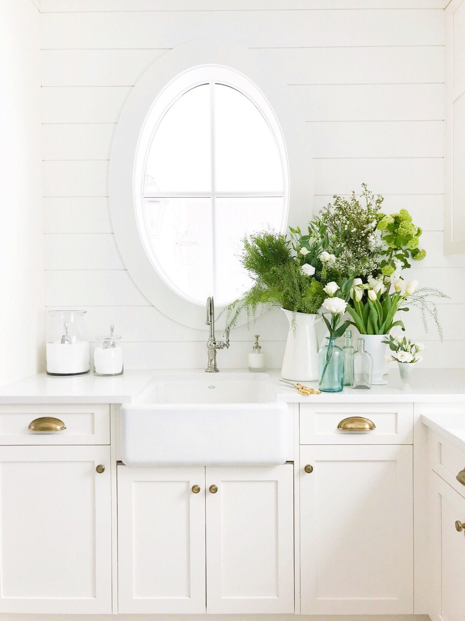 Crisp white laundry room filled with green and white flowers perfect for St. Patrick's Day!