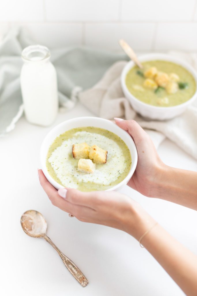 hands holding a bowl of Potato Broccoli Soup 
