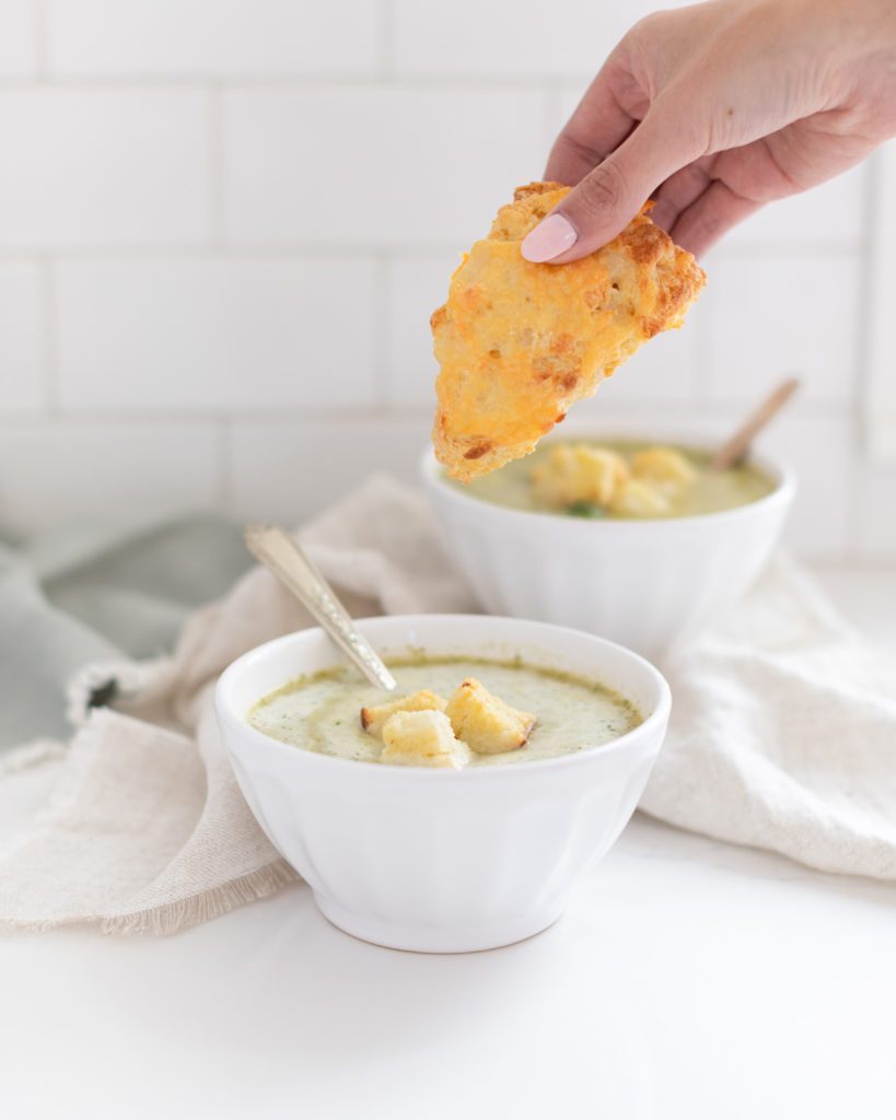hand dipping in a scone to Potato Broccoli Soup