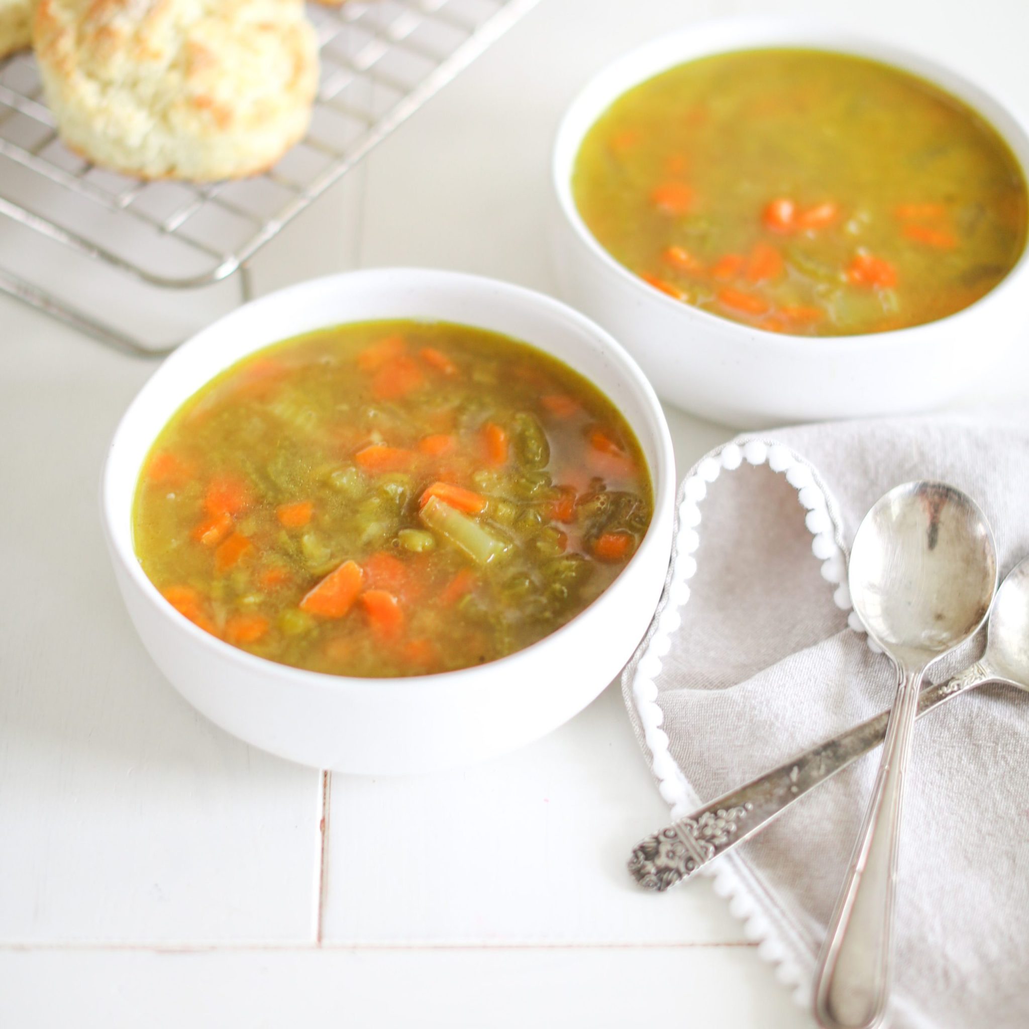 split pea soup with carrots, on white wooden table with spoons