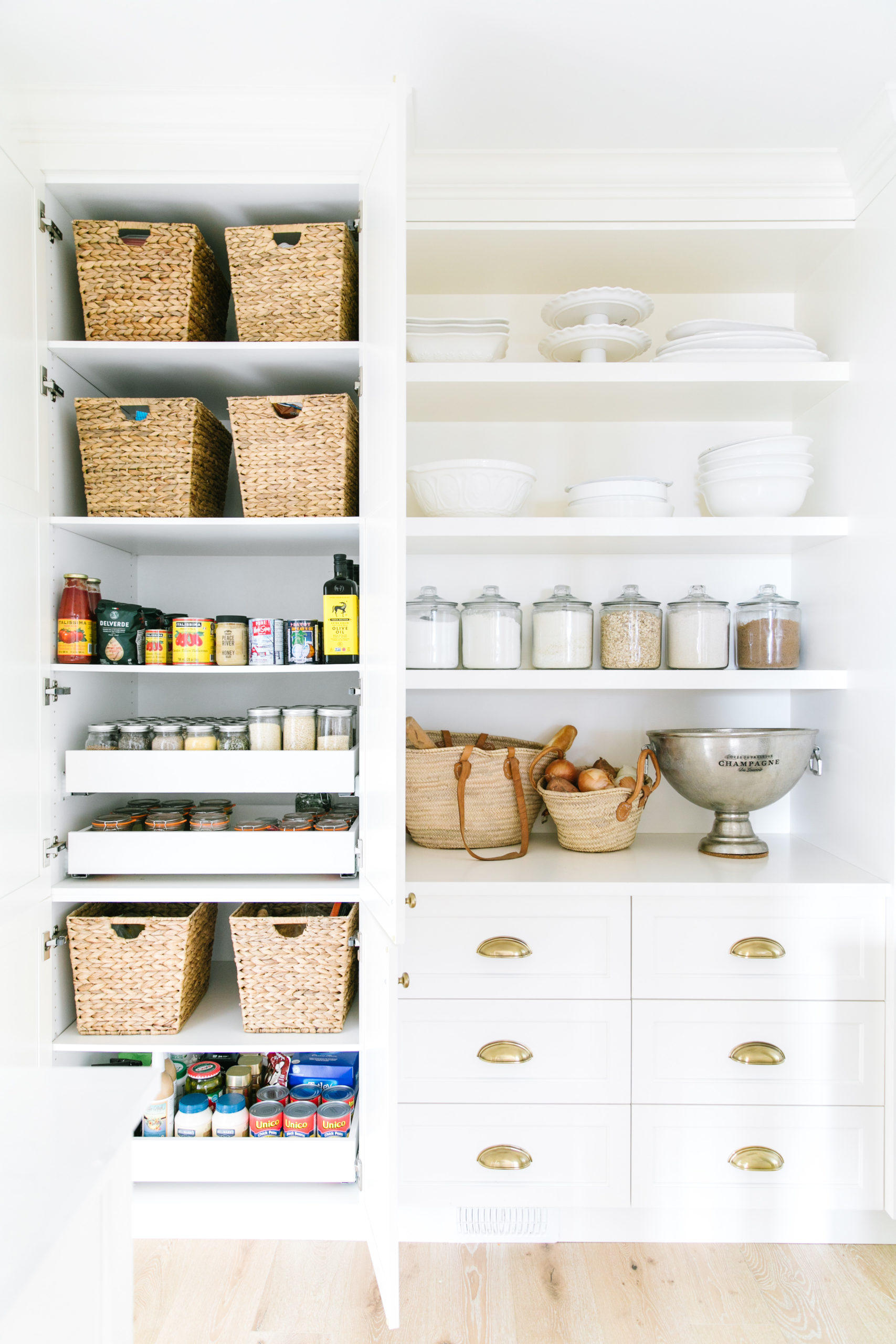Our white butler's pantry reveal with an arched doorway, vintage chandelier lighting and open shelving with these white bowls, baskets and glass jars for storage!
