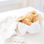 homemade pita bread in a white basket with white cloth on white table