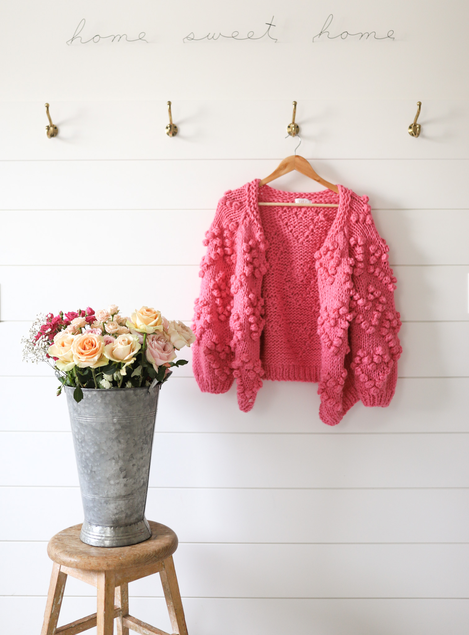 pink sweater hanging beside a bouquet of flowers