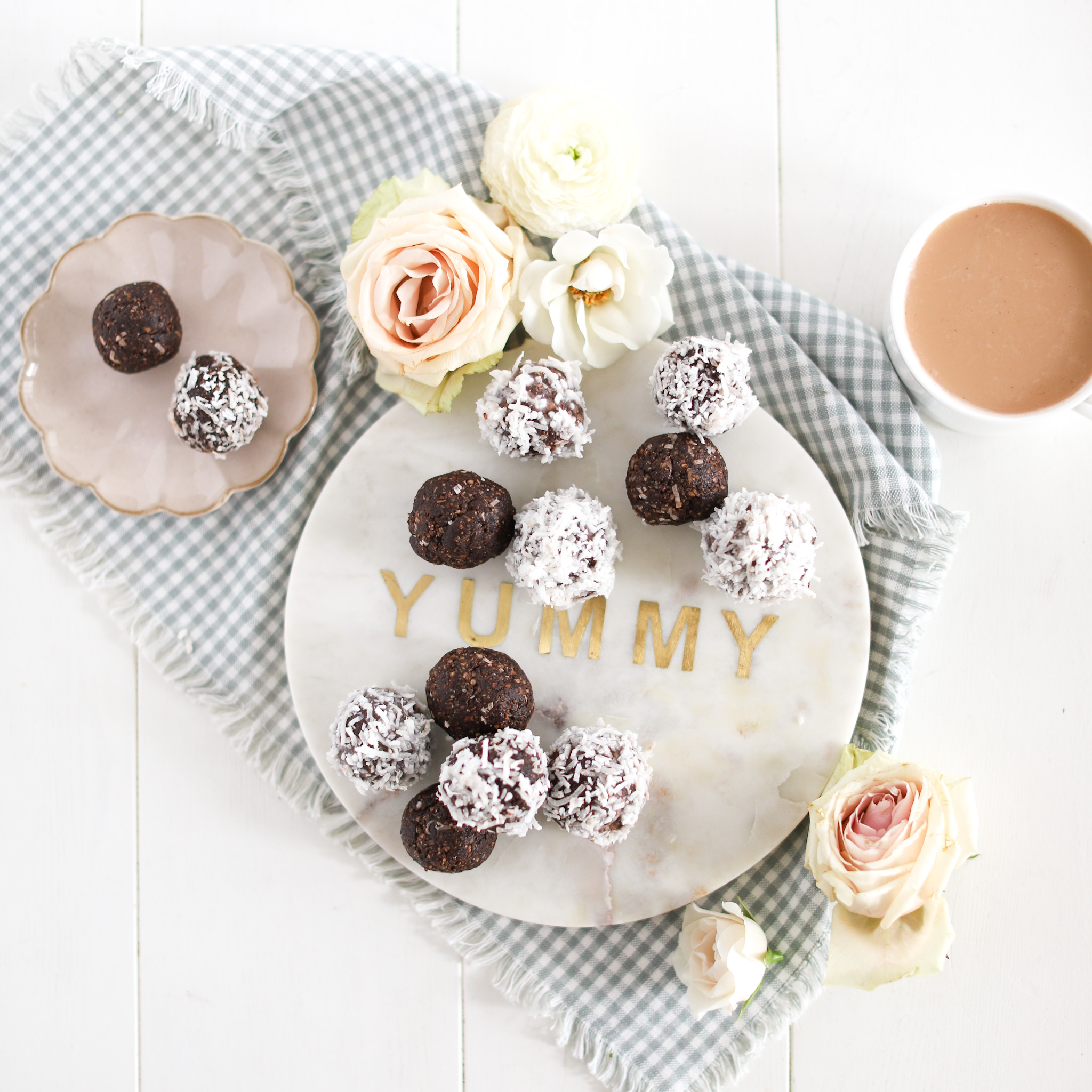 almond joy energy balls on a tray with cup of tea and flowers