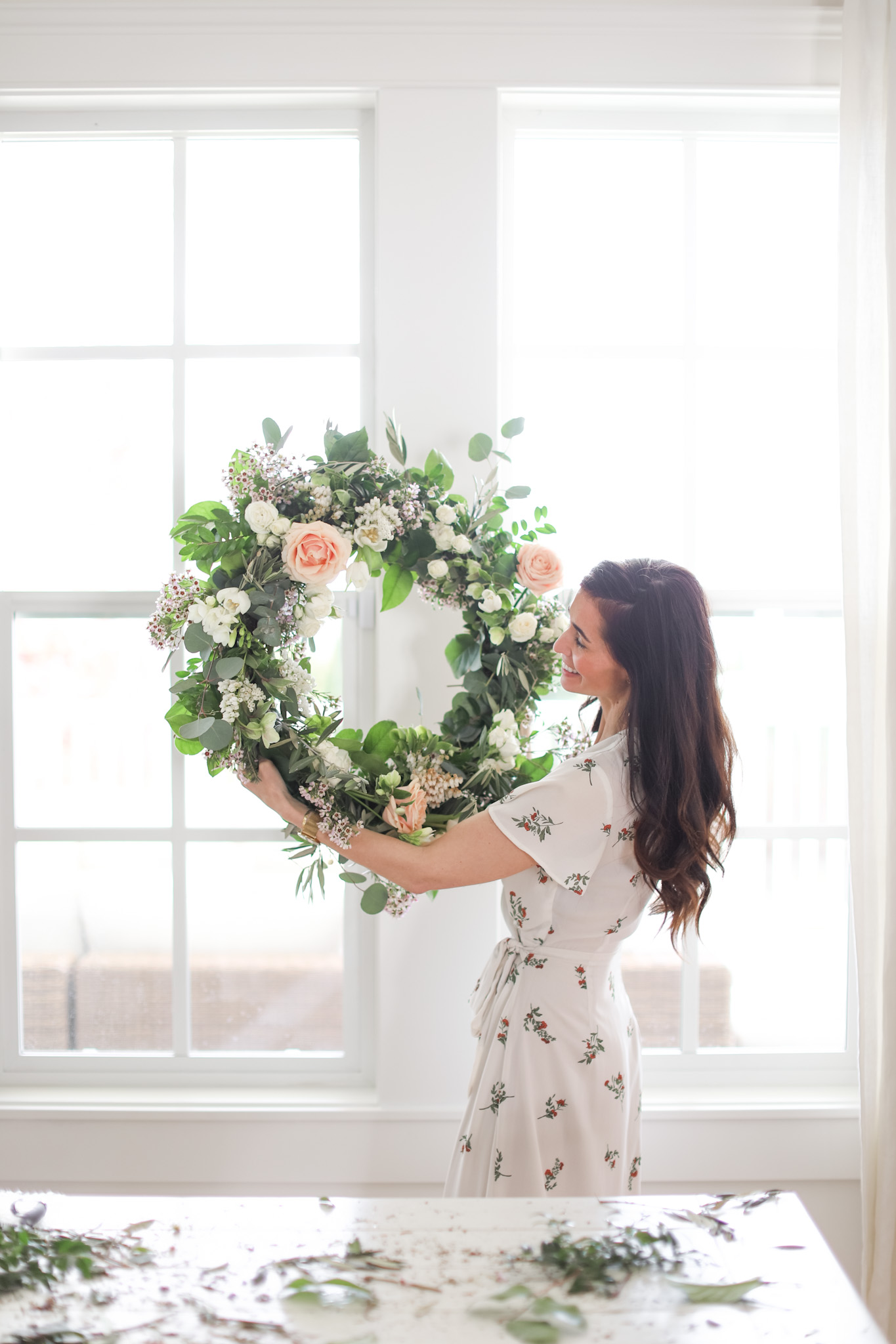 Tori Wesszer Fraiche Living holding completed floral wreath in a white dress