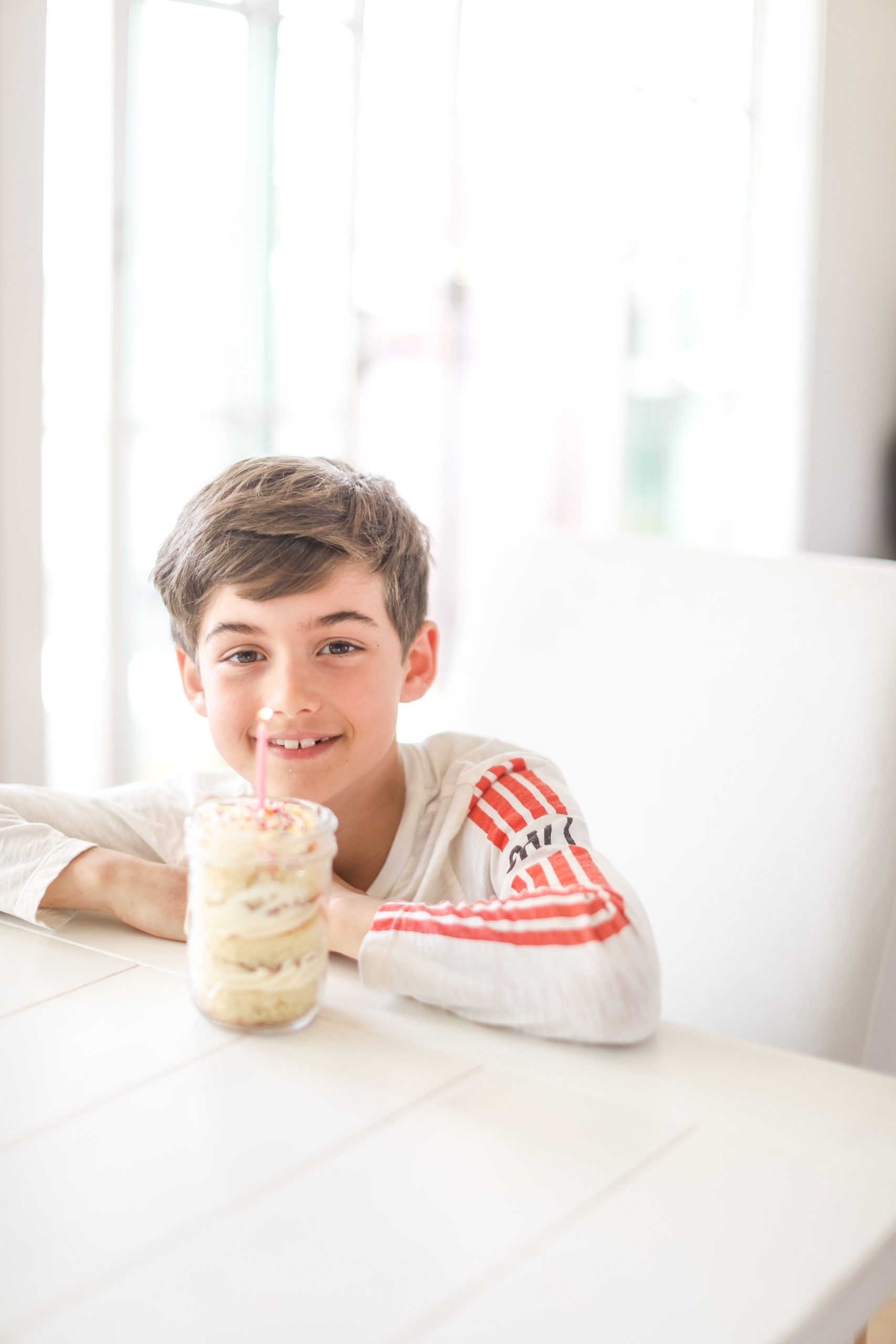 Boy smiling with birthday cake in a jar and candle