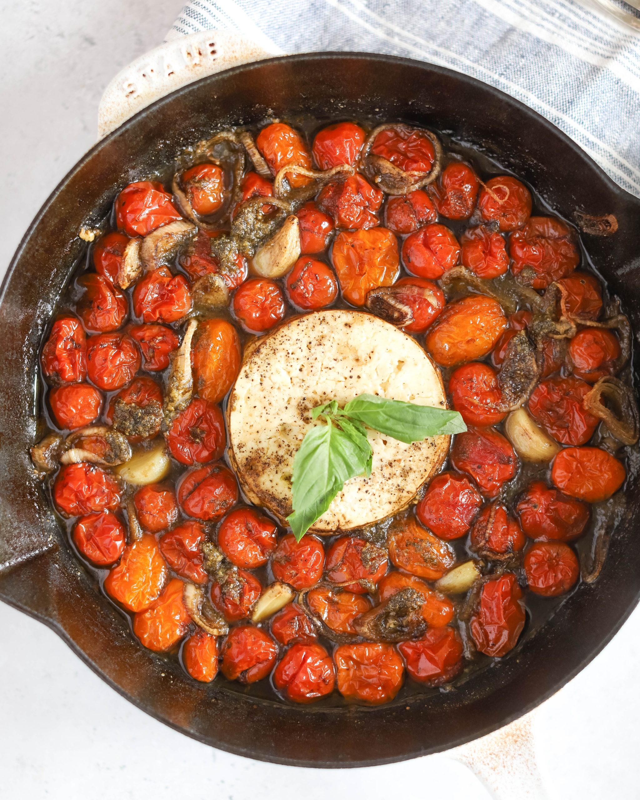 Baked feta dip with roasted tomatoes and basil in a skillet