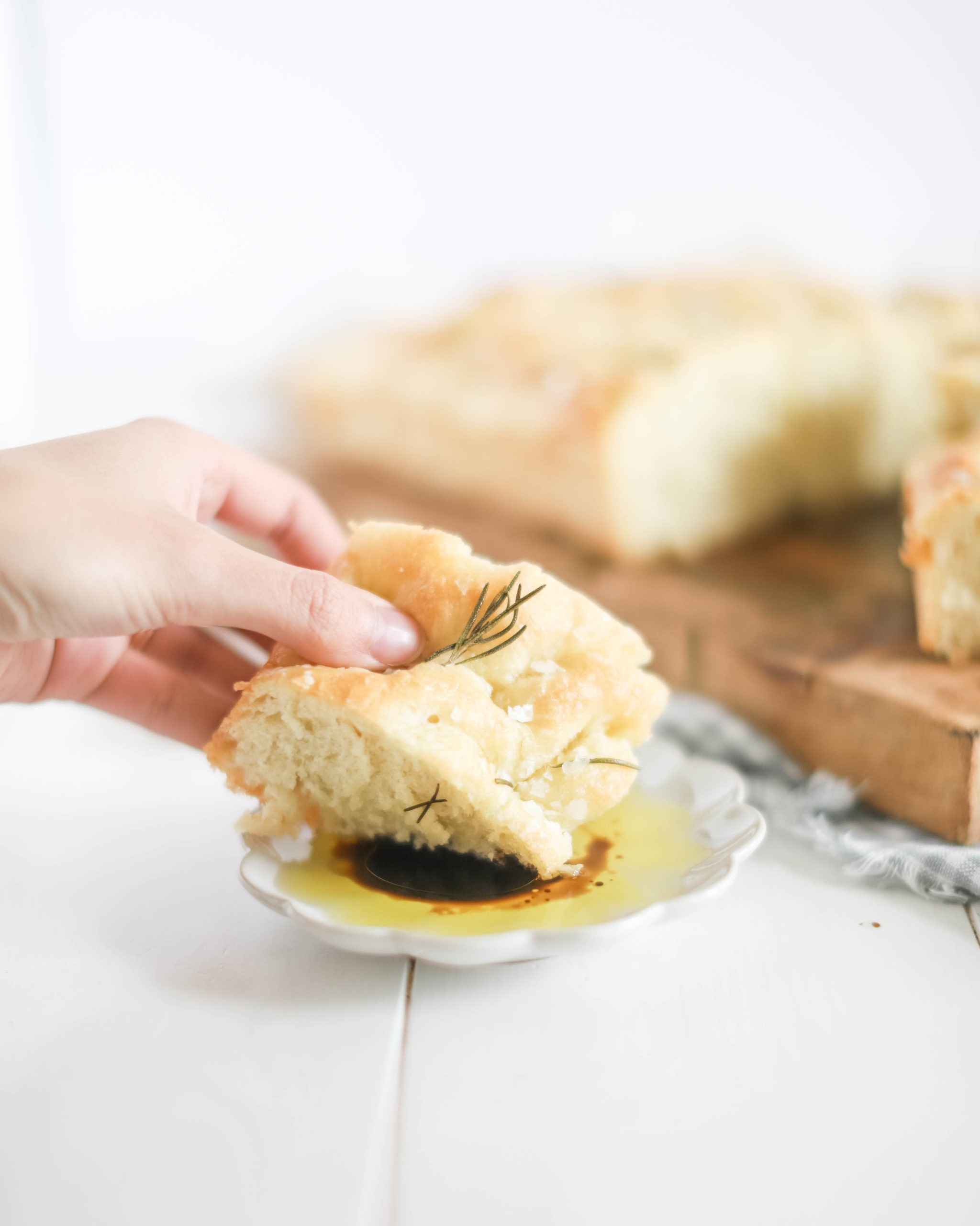 hand grabbing piece of focaccia and dipping in olive oil and balsamic