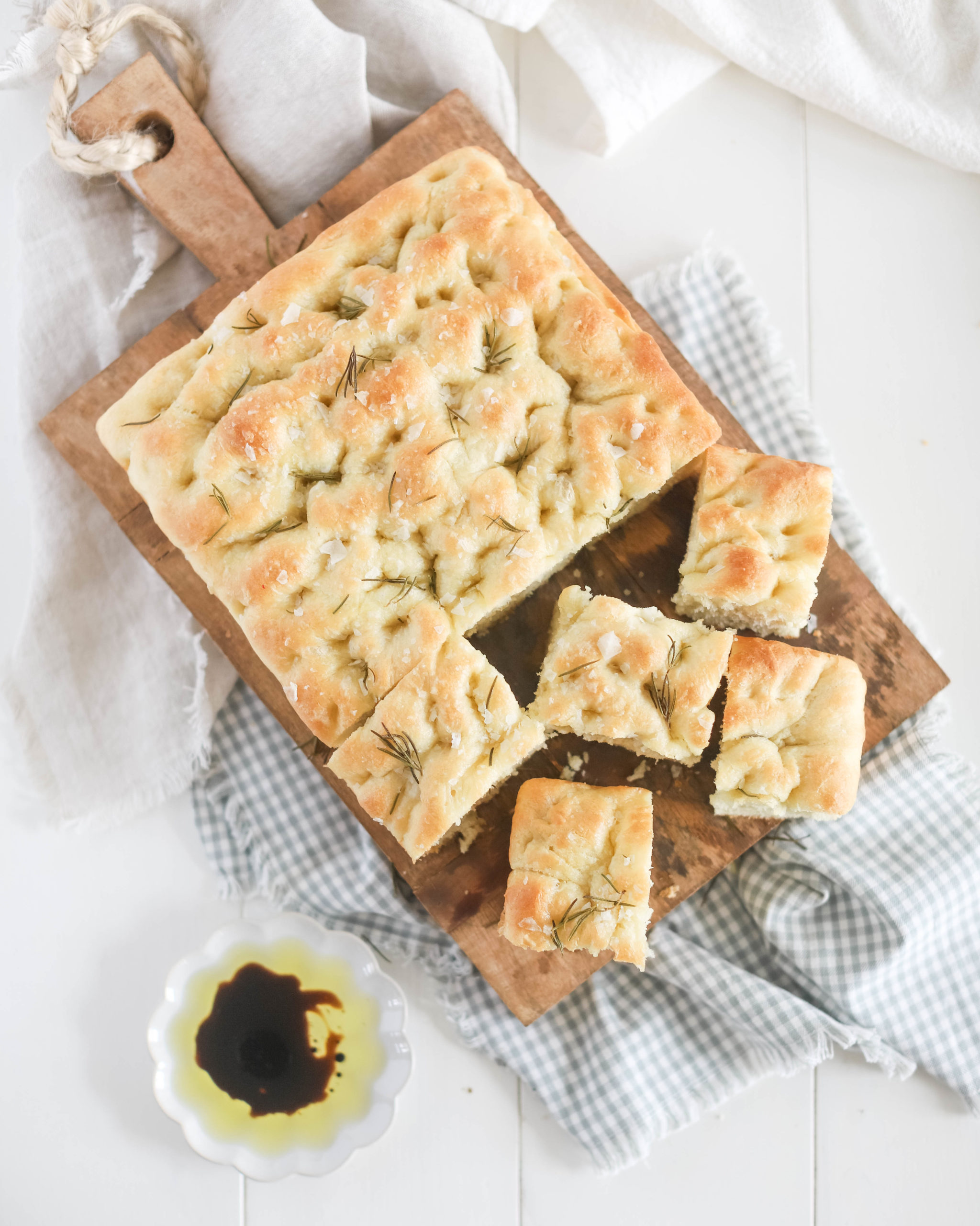 focaccia sliced on a board with bowl of olive oil and balsamic