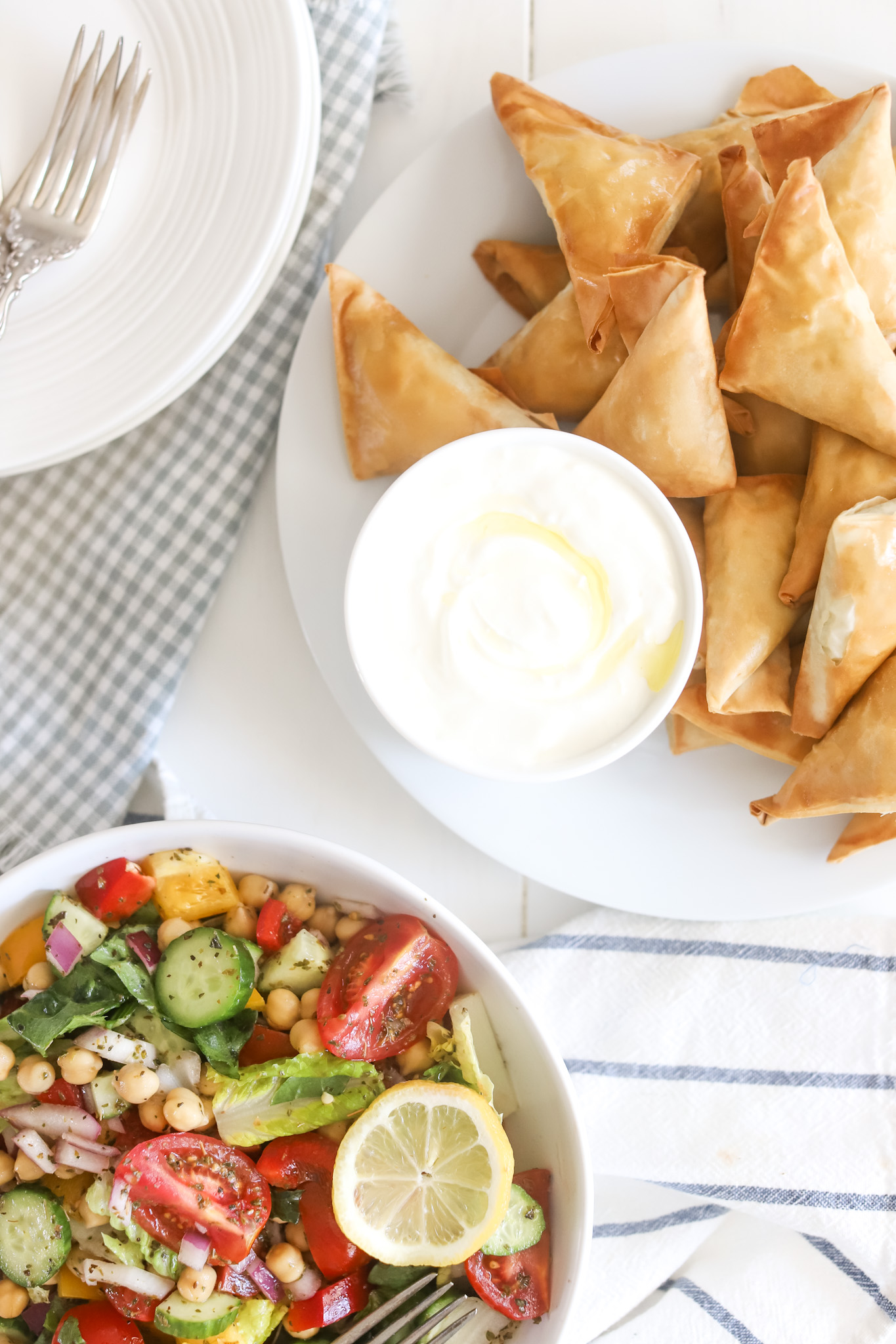 green greek salad in bowl with tzatziki and spinach pies