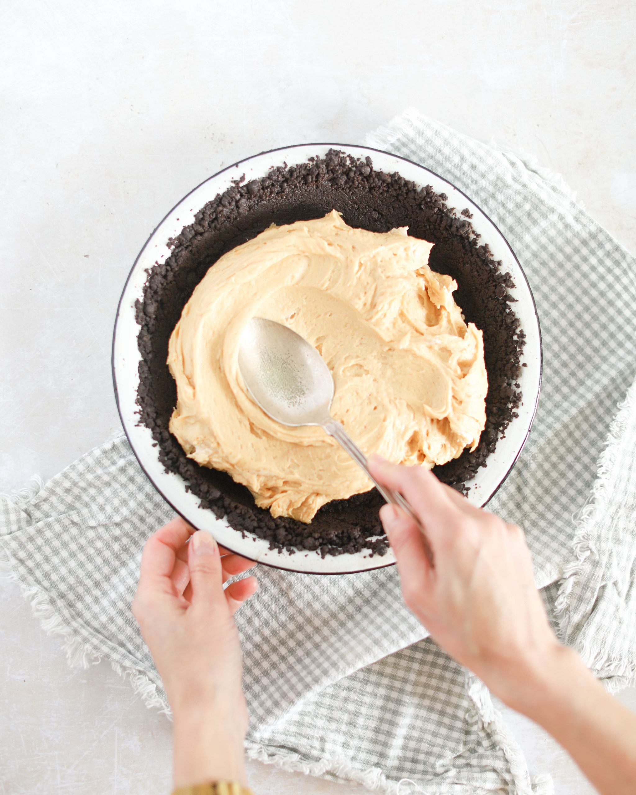 using a spoon to spread filling in pie crust for peanut butter pie