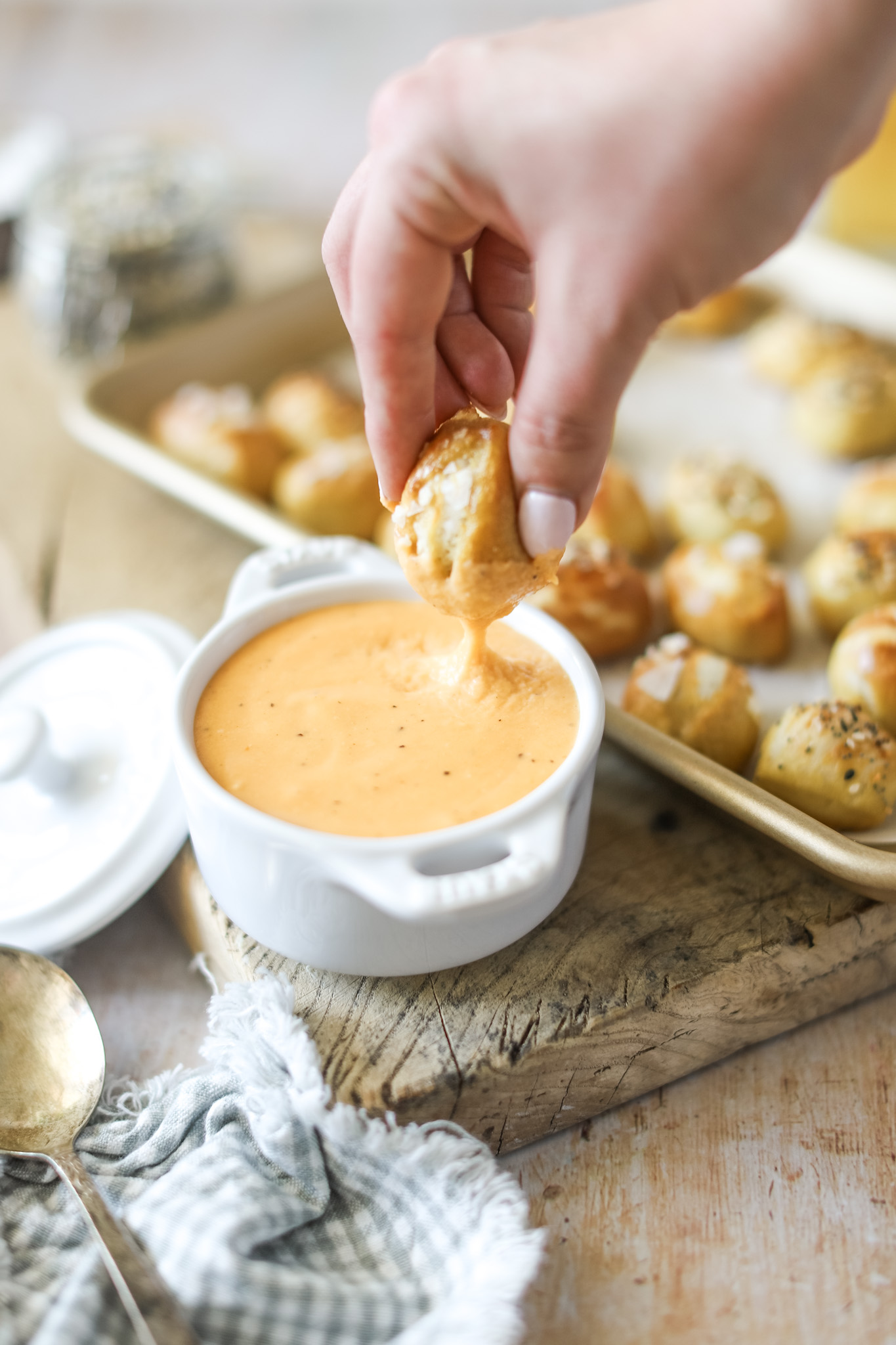 Hand dipping soft pretzel bites into beer cheese dip 