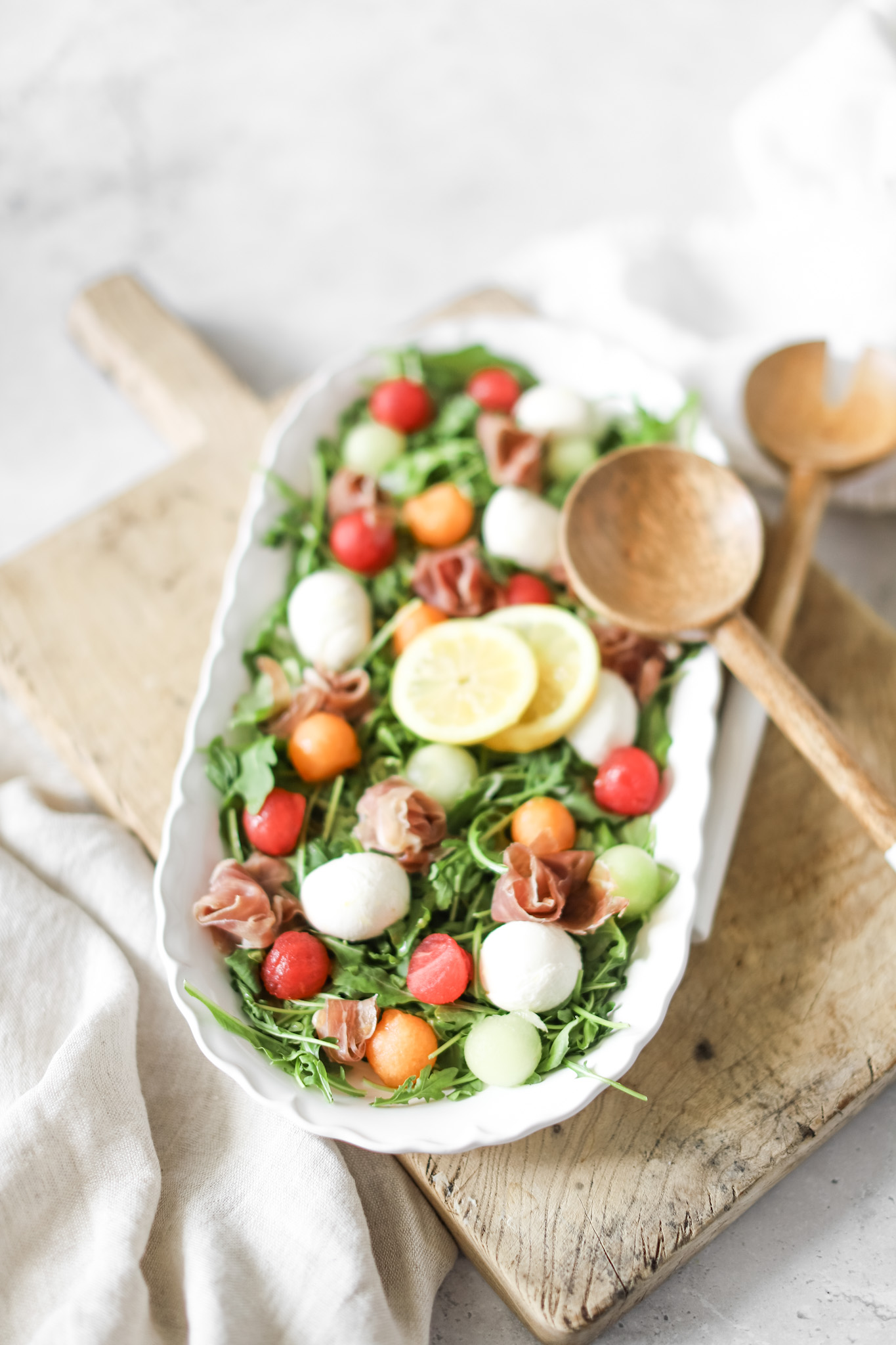 prosciutto melon salad in a bowl with serving spoons