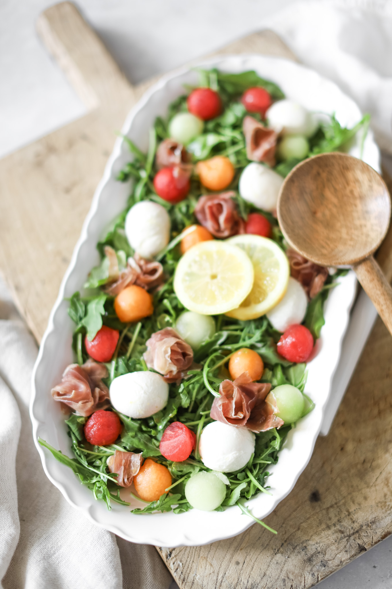 prosciutto melon salad in a bowl with serving spoons