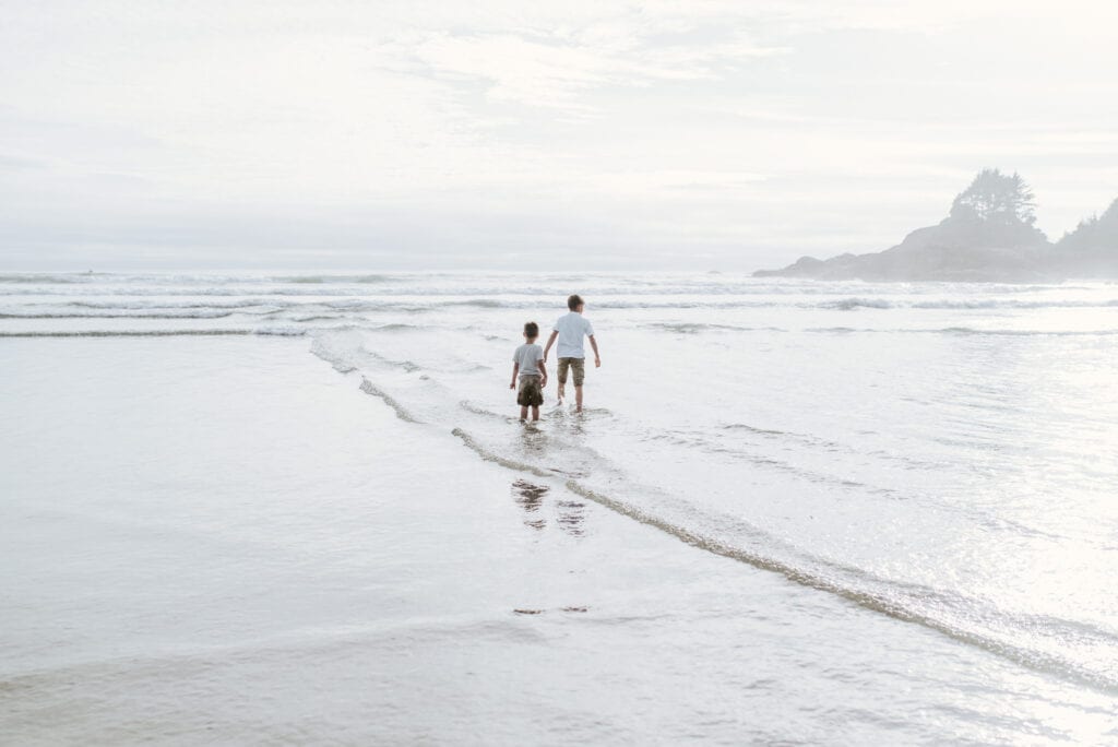 two boys walking along beach in Tofino