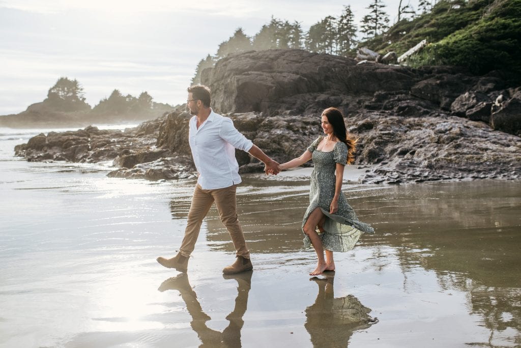 couple waling along beach in Tofino at sunset
