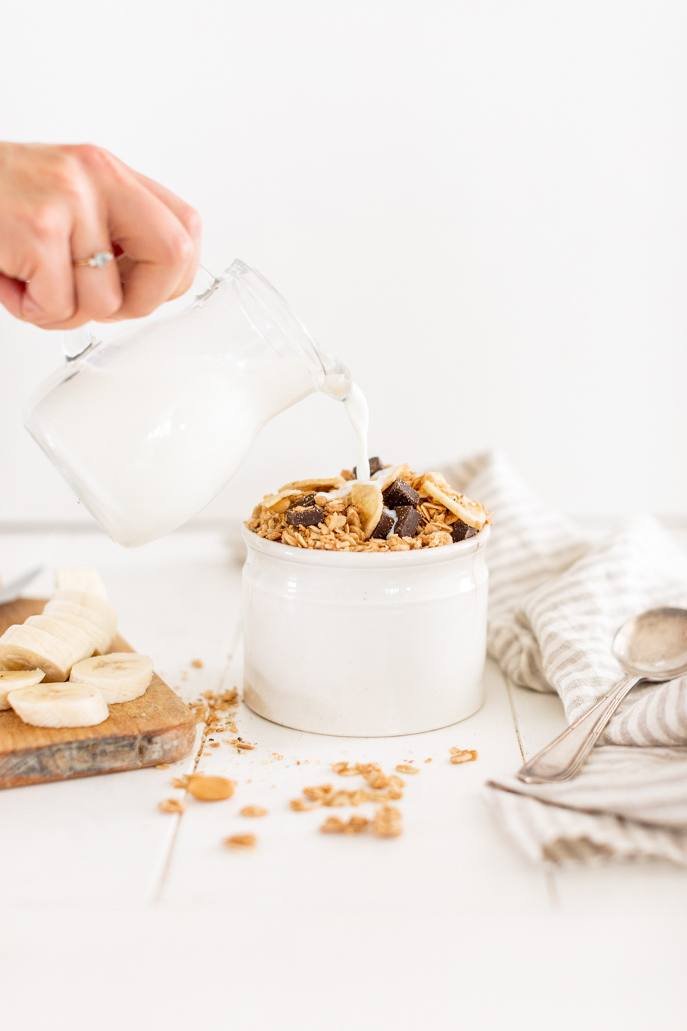 Chunky Monkey Granola by Fraiche Living in a bowl with hand pouring in milk