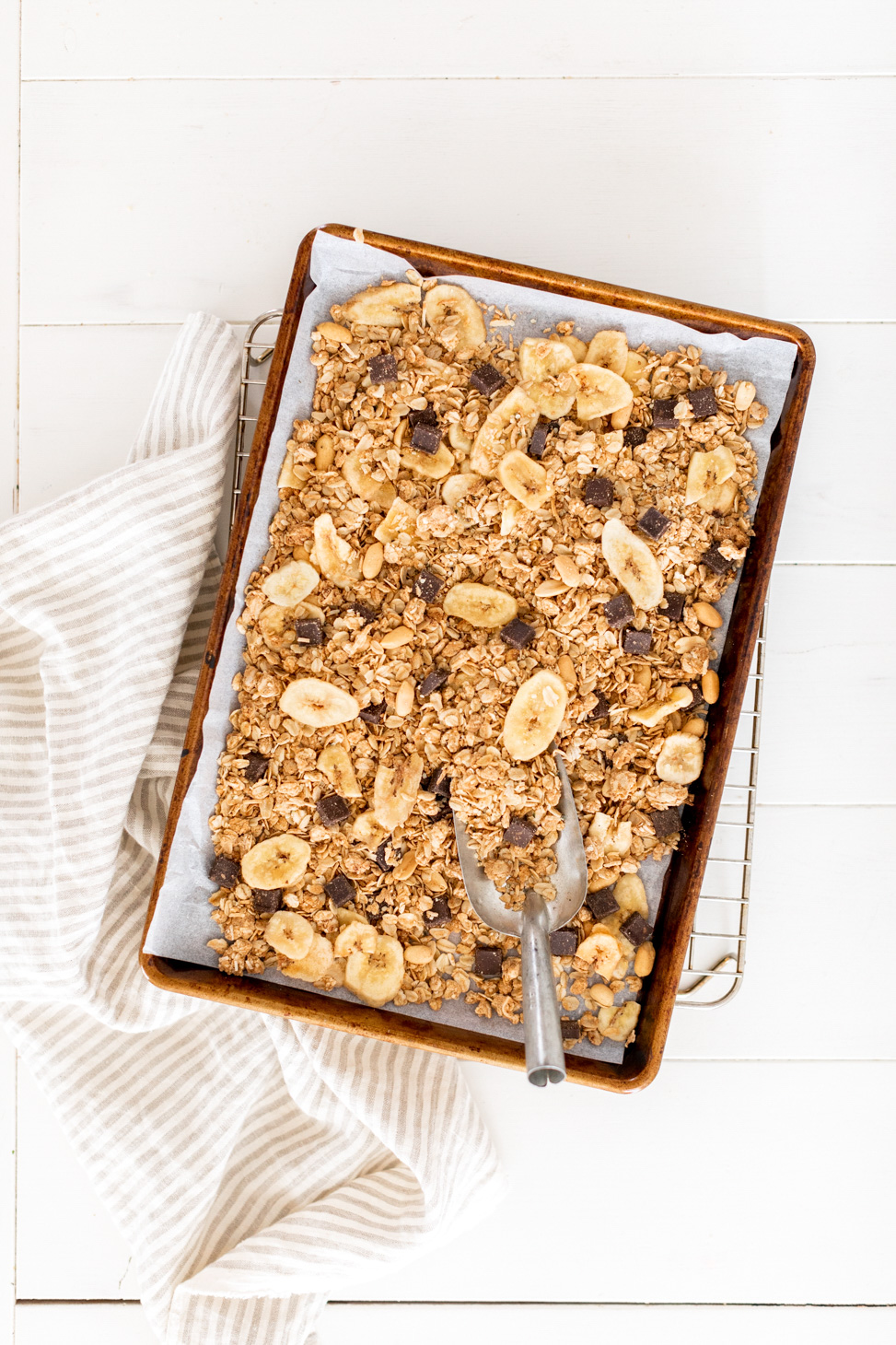Chunky Monkey Granola by Fraiche Living on a sheet pan with scoop