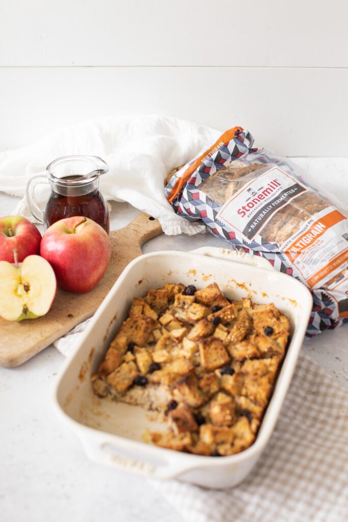 Baked Apple Cinnamon French Toast in a casserole dish with apples and maple syrup