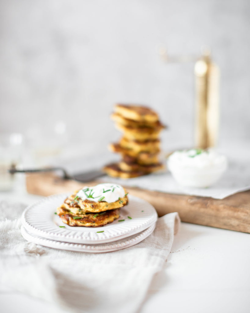 Spaghetti Squash Fritters on a plate topped with sour cream and chives