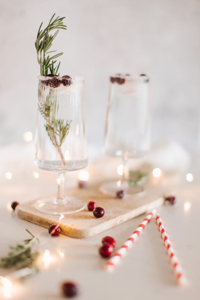 two glasses of sparkling SodaStream water with cranberries and rosemary